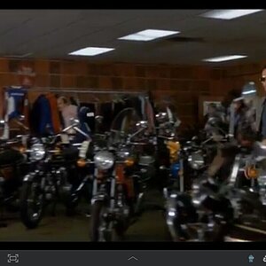 Mr. Oates strolls across the sales showroom, Fred looking on.
Early '75 motorcycles everywhere...