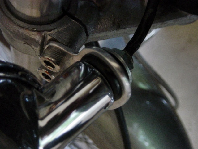 Bobbed turn signal housing attached to lower fork clamp using custom "mule ear" bracket designed for sleeve-and-grommet anti-vibration mounting method